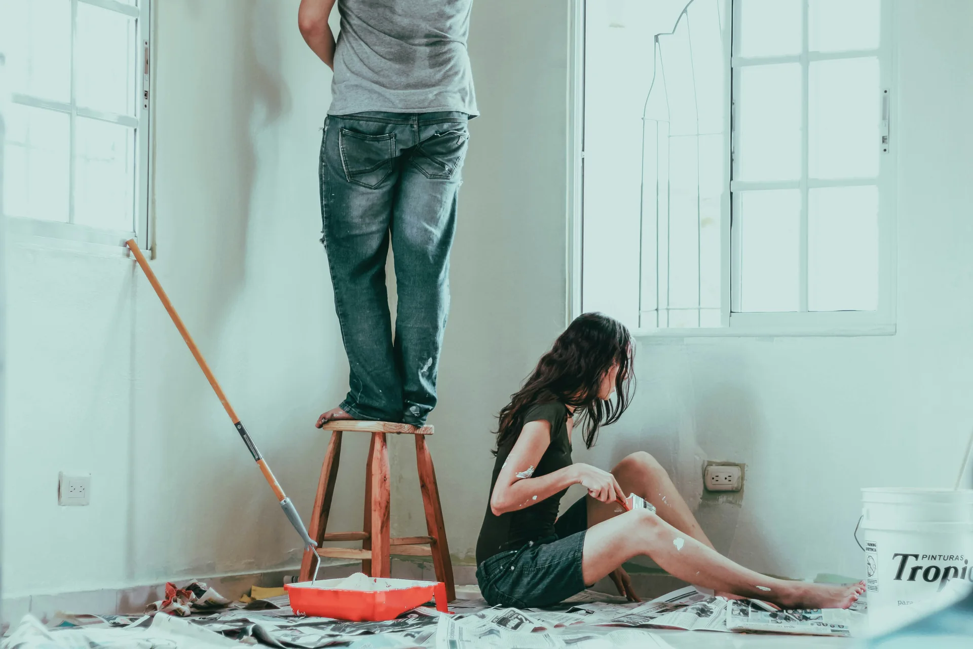 People painting a bright interior room