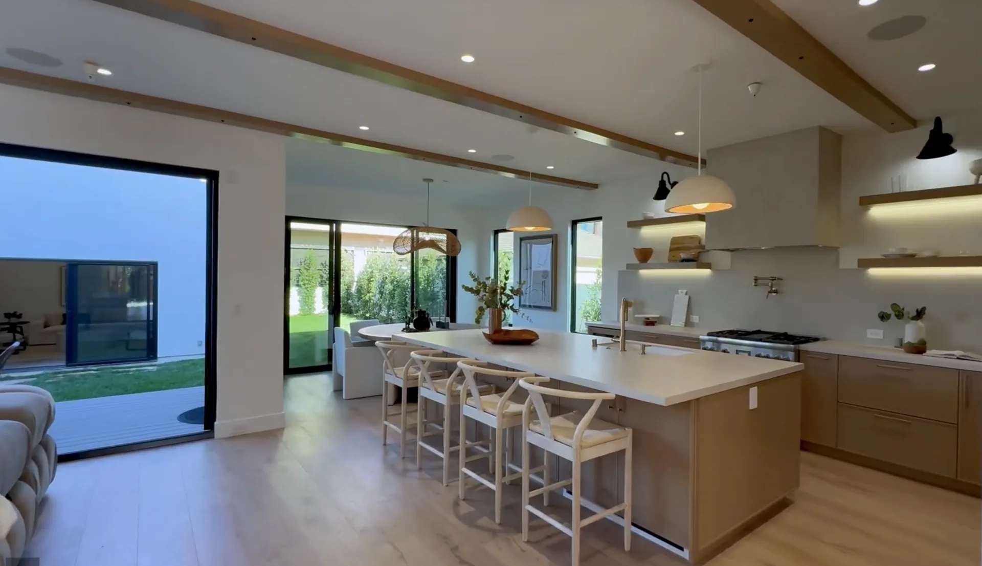 A luxury kitchen with a large island, warm wood cabinetry, pendant lighting, and sliding doors